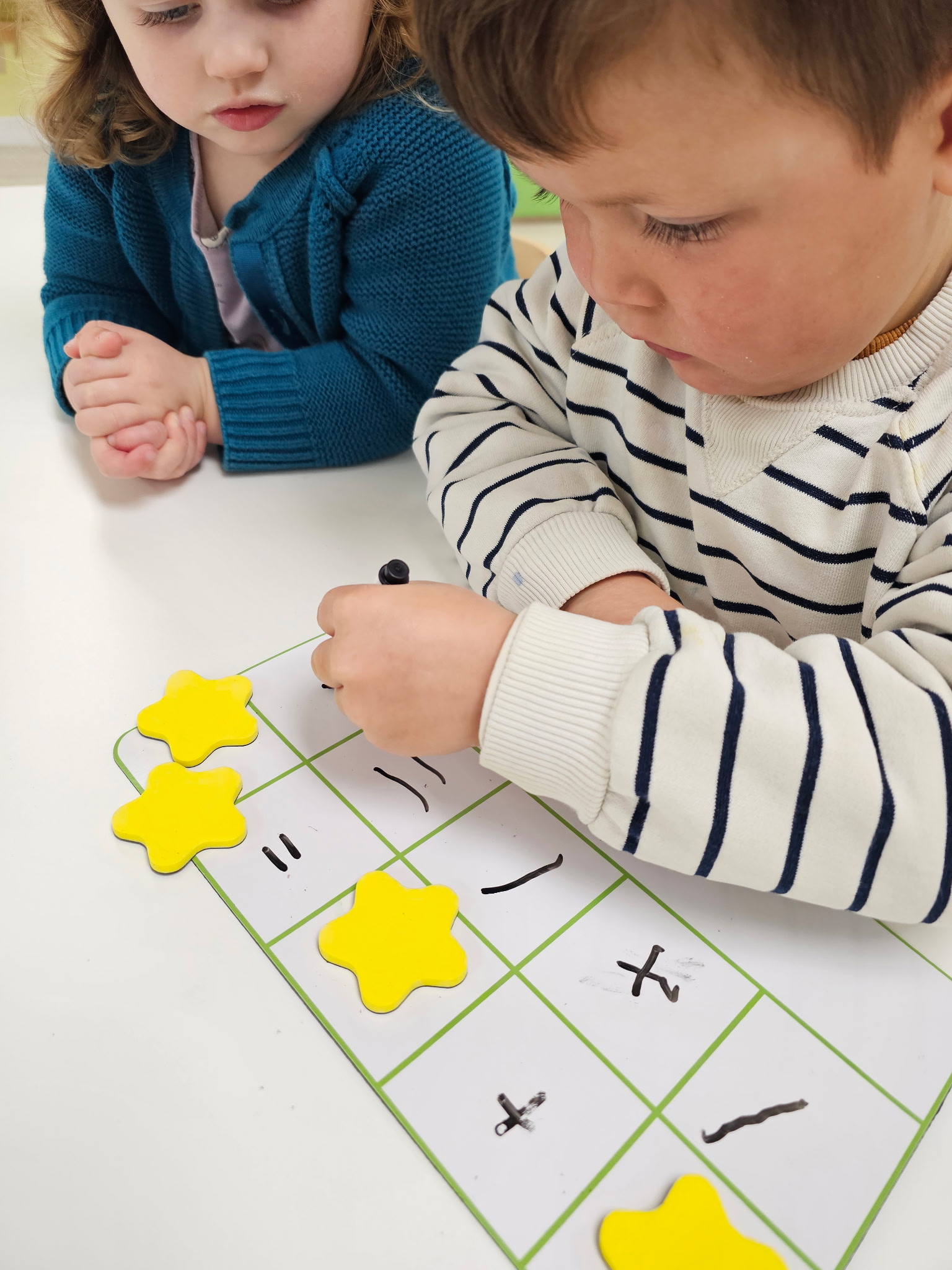 The outdoor classroom — lush green yard with garden beds, sand table, and climbing structure