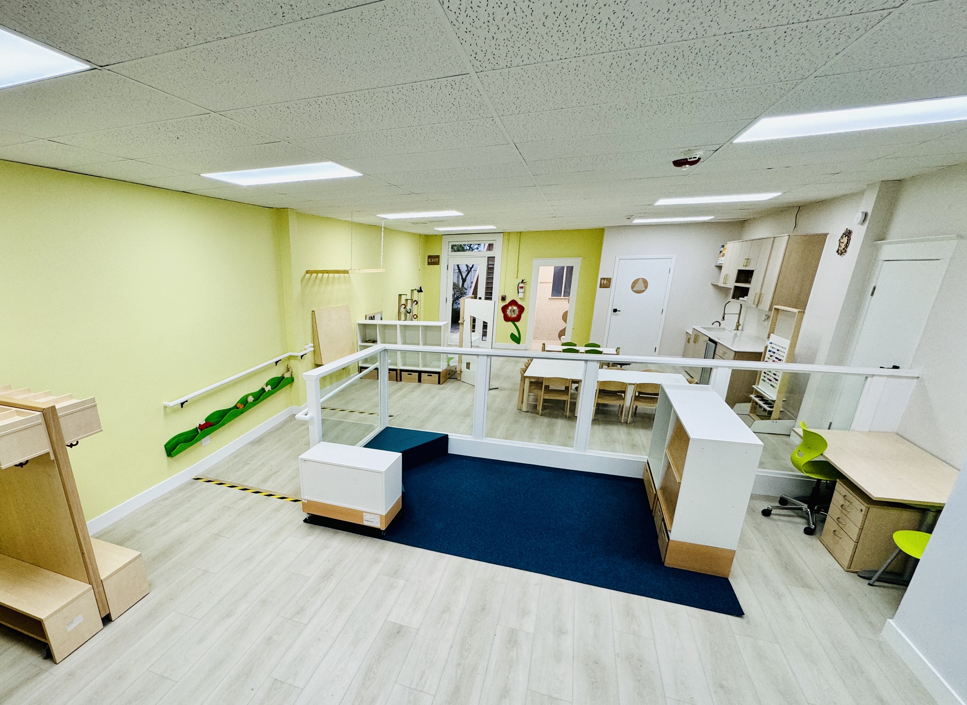 Calm, light-filled classroom with child-sized Montessori shelving and warm natural materials