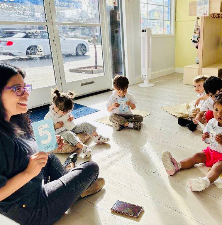 Priscila leading a group lesson with children seated in a circle